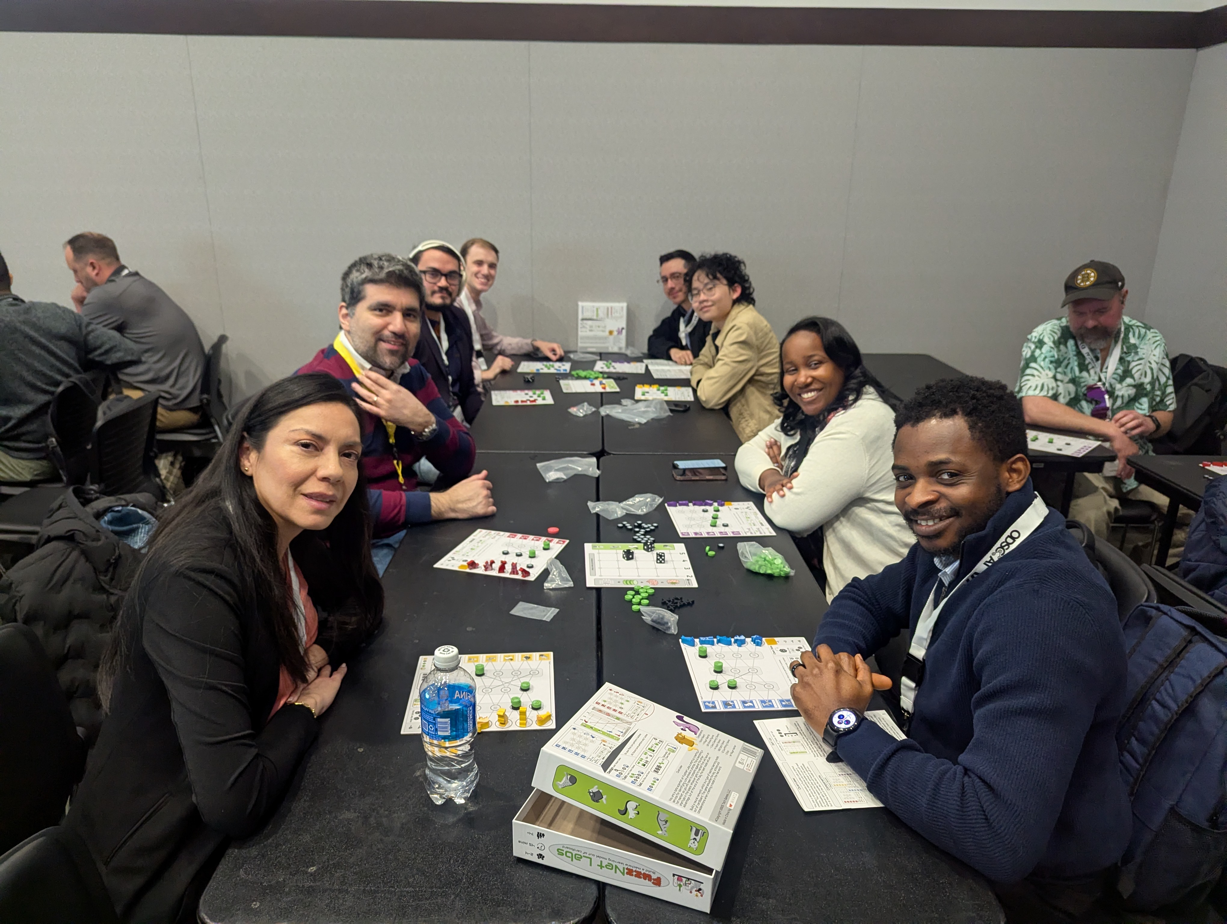Four participants smiling while playing FuzzNet Labs around a table